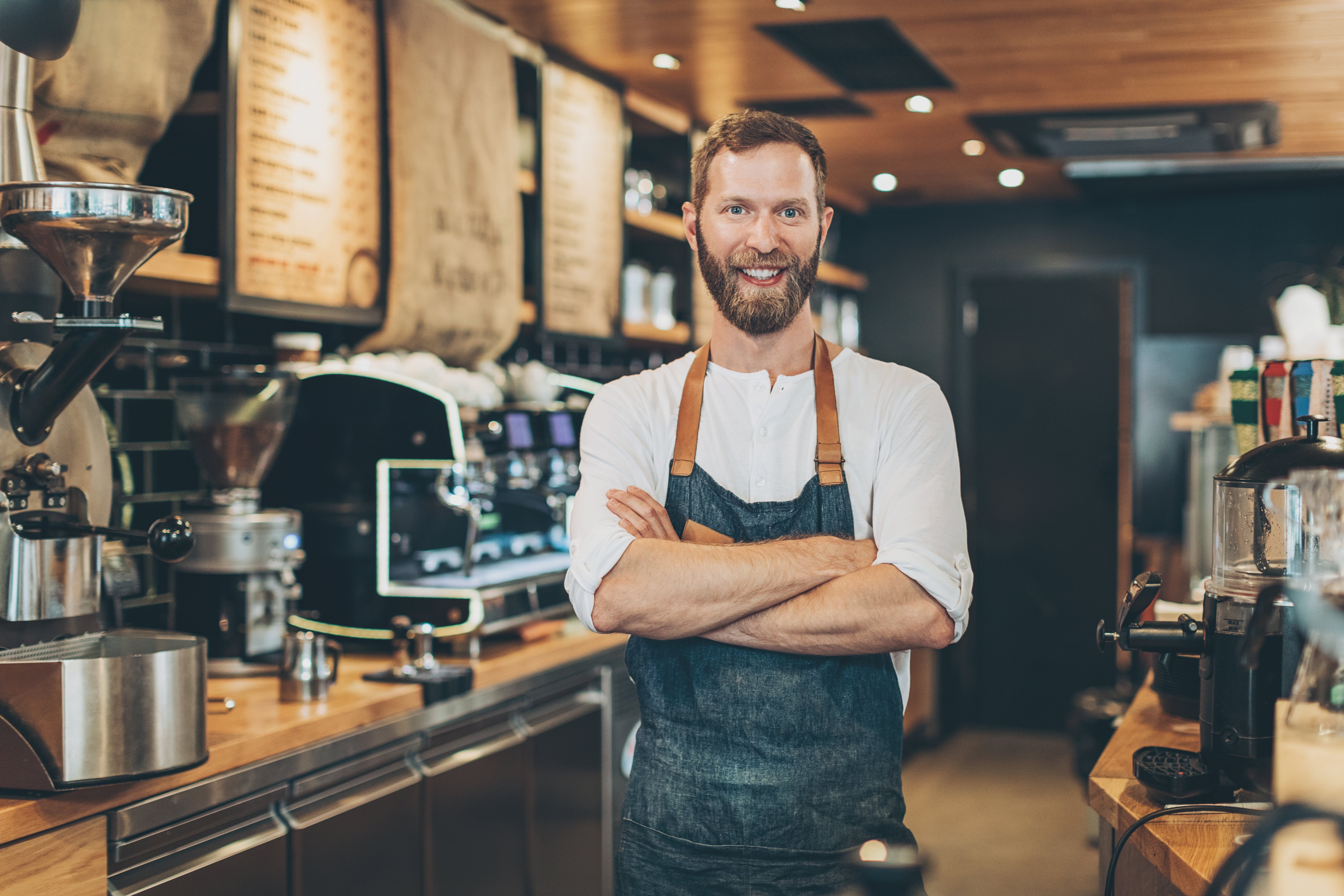 un collaborateur barbu se tient devant un comptoir de café en souriant